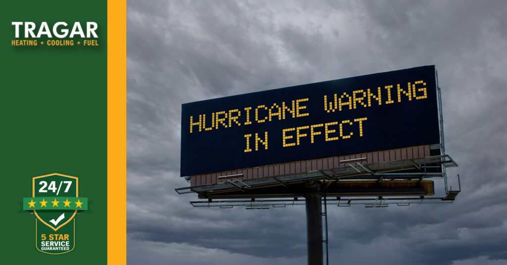 A digital billboard displays "Hurricane Warning In Effect" against a cloudy sky.