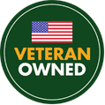 Circular badge with a small American flag above the words “Veteran Owned” in bold yellow and white letters on a dark green background.